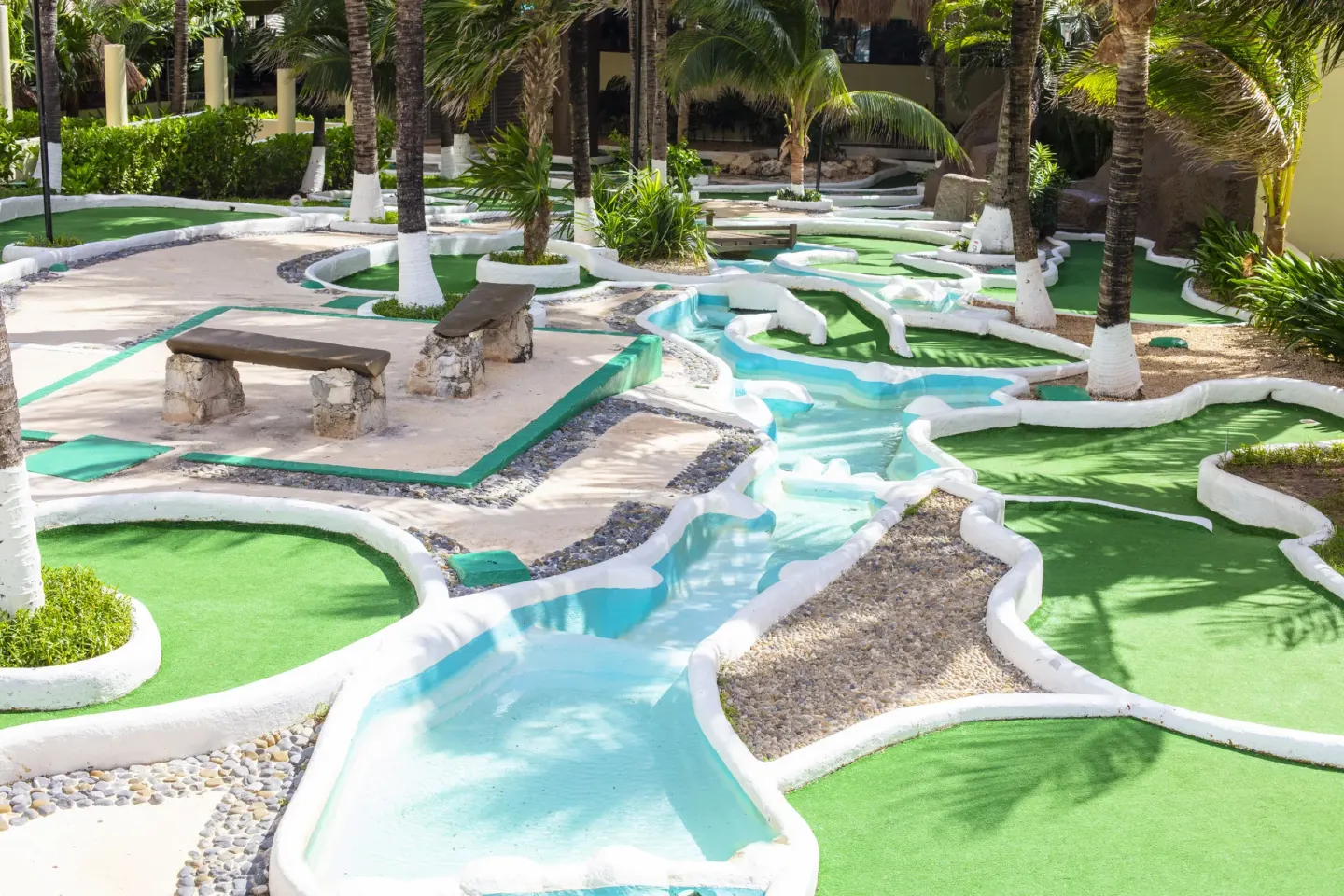 Mini golf course with palm trees and winding paths at Crown Paradise Club Cancun.