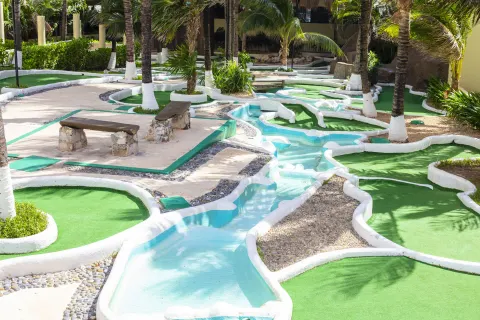 Mini golf course with palm trees and winding paths at Crown Paradise Club Cancun.