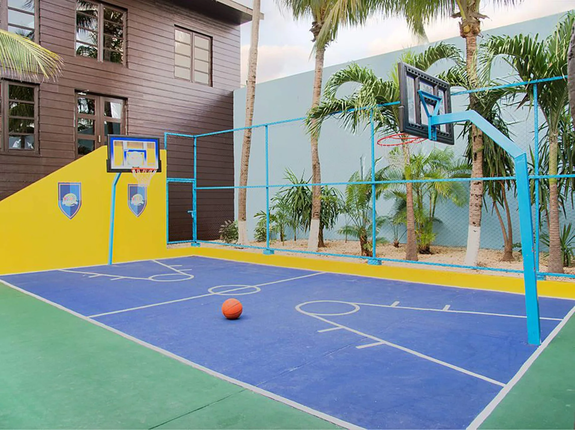 Small outdoor basketball court with palm trees at Crown Paradise Club Cancun.