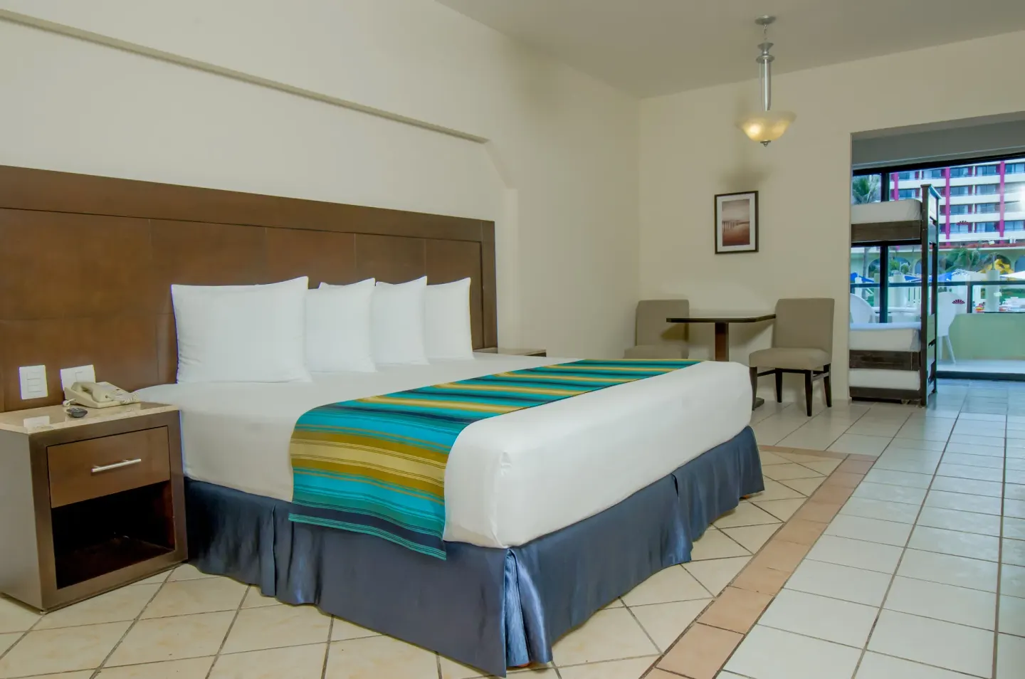Family Suite Crown room with king bed, table, and balcony bunk area at Crown Paradise Club Cancun.