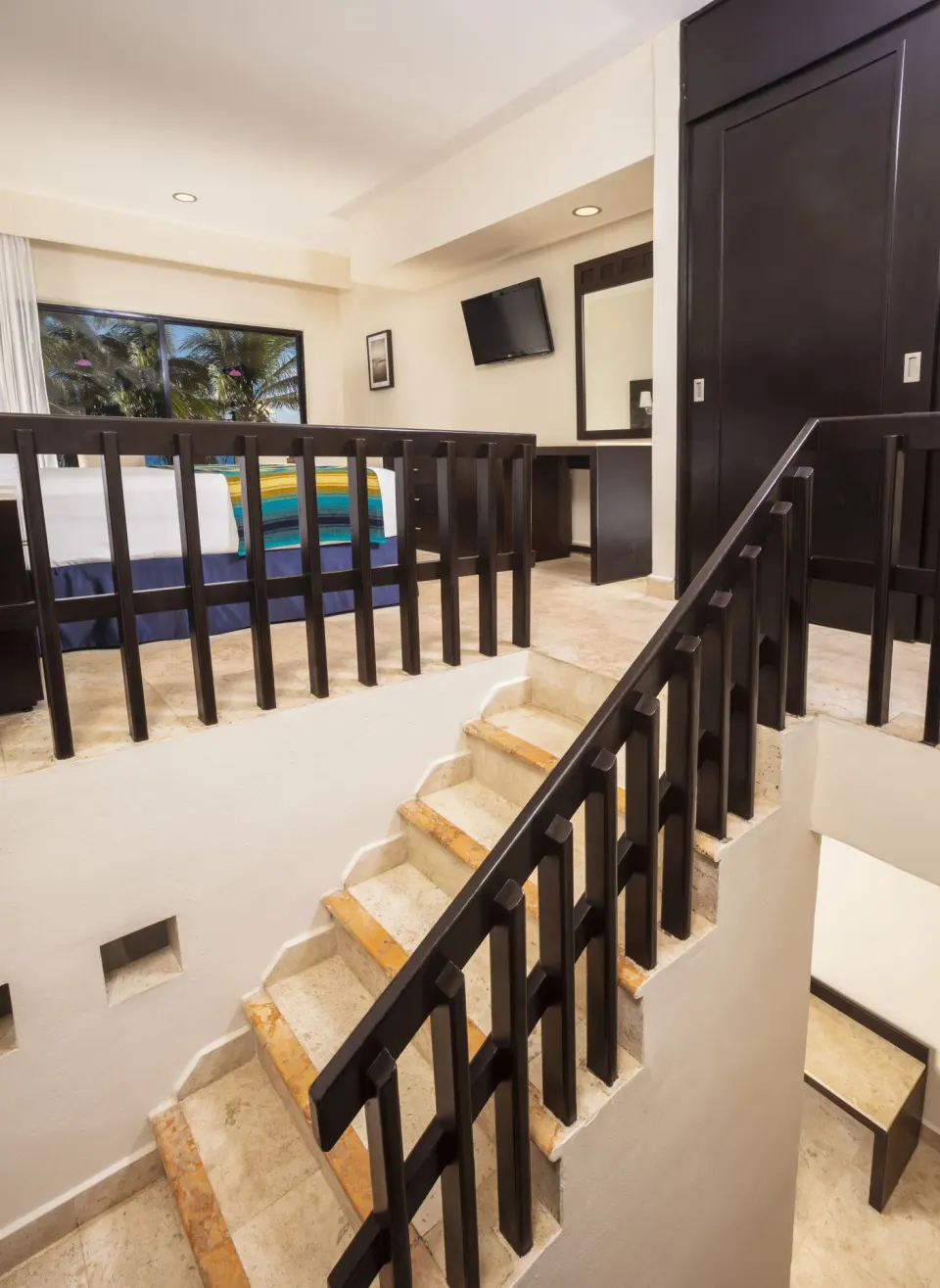 Split-level Family Suite Paradise with stairs and bedroom area at Crown Paradise Club Cancun.