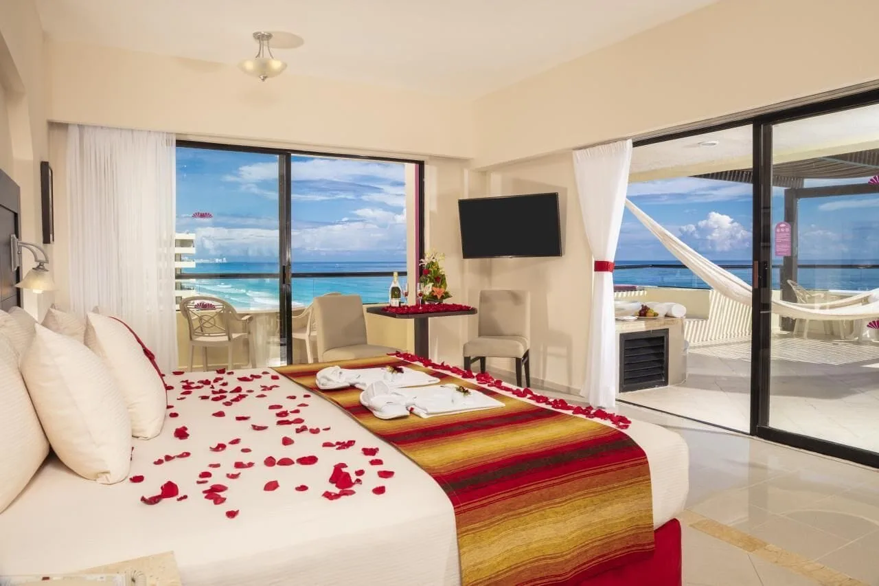 Honeymoon Room king bed with rose petals and ocean terrace at Crown Paradise Club Cancun.