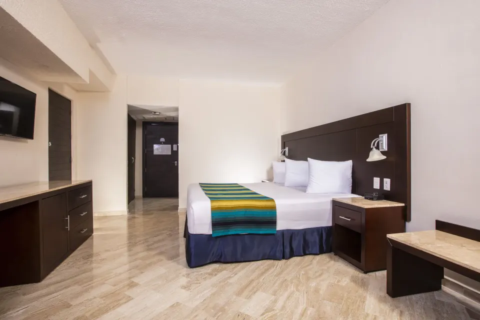 Standard Ocean View king room with entry door and dresser at Crown Paradise Club Cancun.