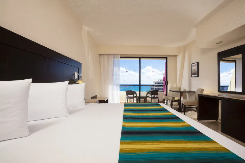 Standard Ocean View king bed with balcony and ocean beyond at Crown Paradise Club Cancun.