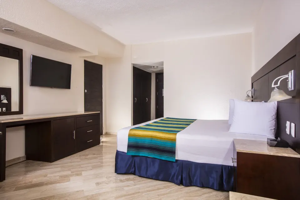 Standard Ocean View room with one king bed and wall-mounted TV at Crown Paradise Club Cancun.