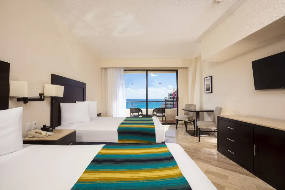 Standard Ocean View room with two beds facing balcony doors at Crown Paradise Club Cancun.