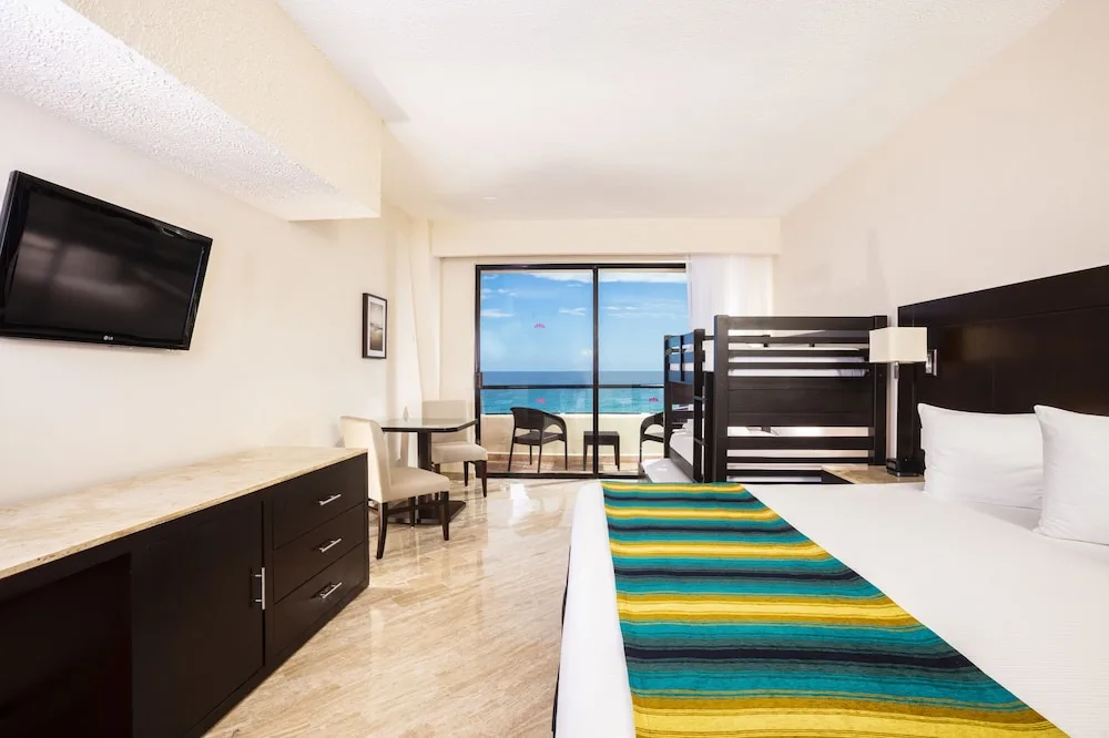 Standard Room with king bed, bunks, balcony and ocean view at Crown Paradise Club Cancun.