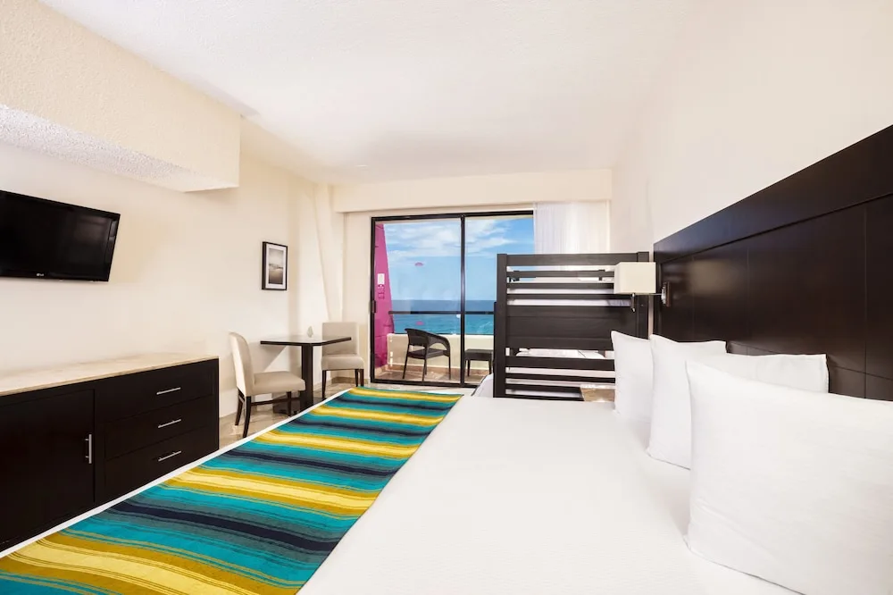 Standard Room with king bed, dark bunk beds and balcony view at Crown Paradise Club Cancun.