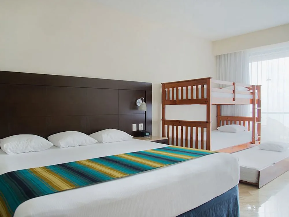 Standard Room king bed and wooden bunk beds at Crown Paradise Club Cancun.
