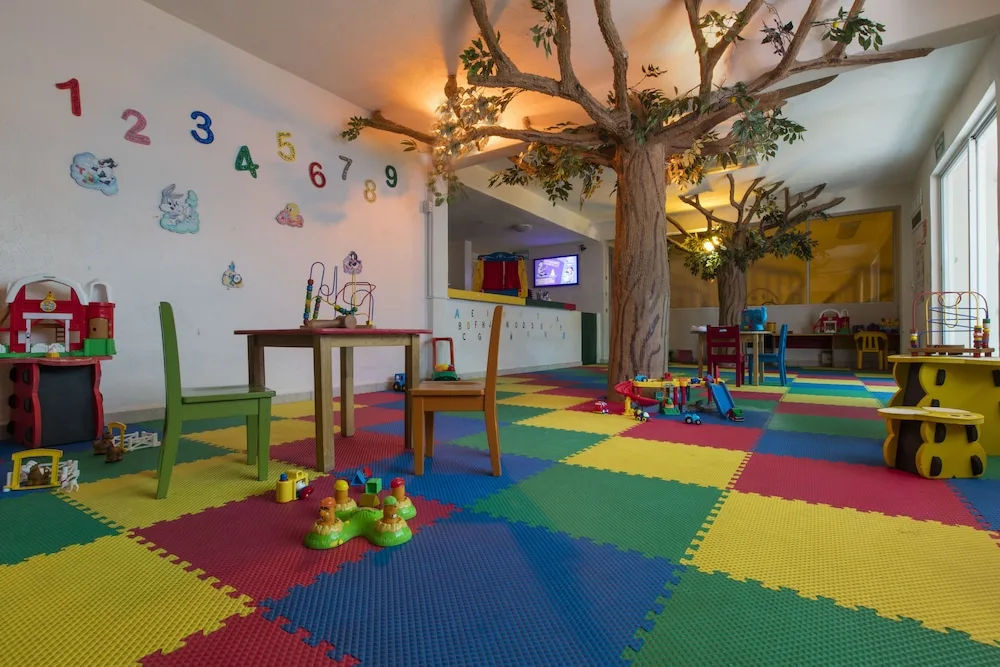 Colorful children's playroom with toys and tree decor at Crown Paradise Club Puerto Vallarta.