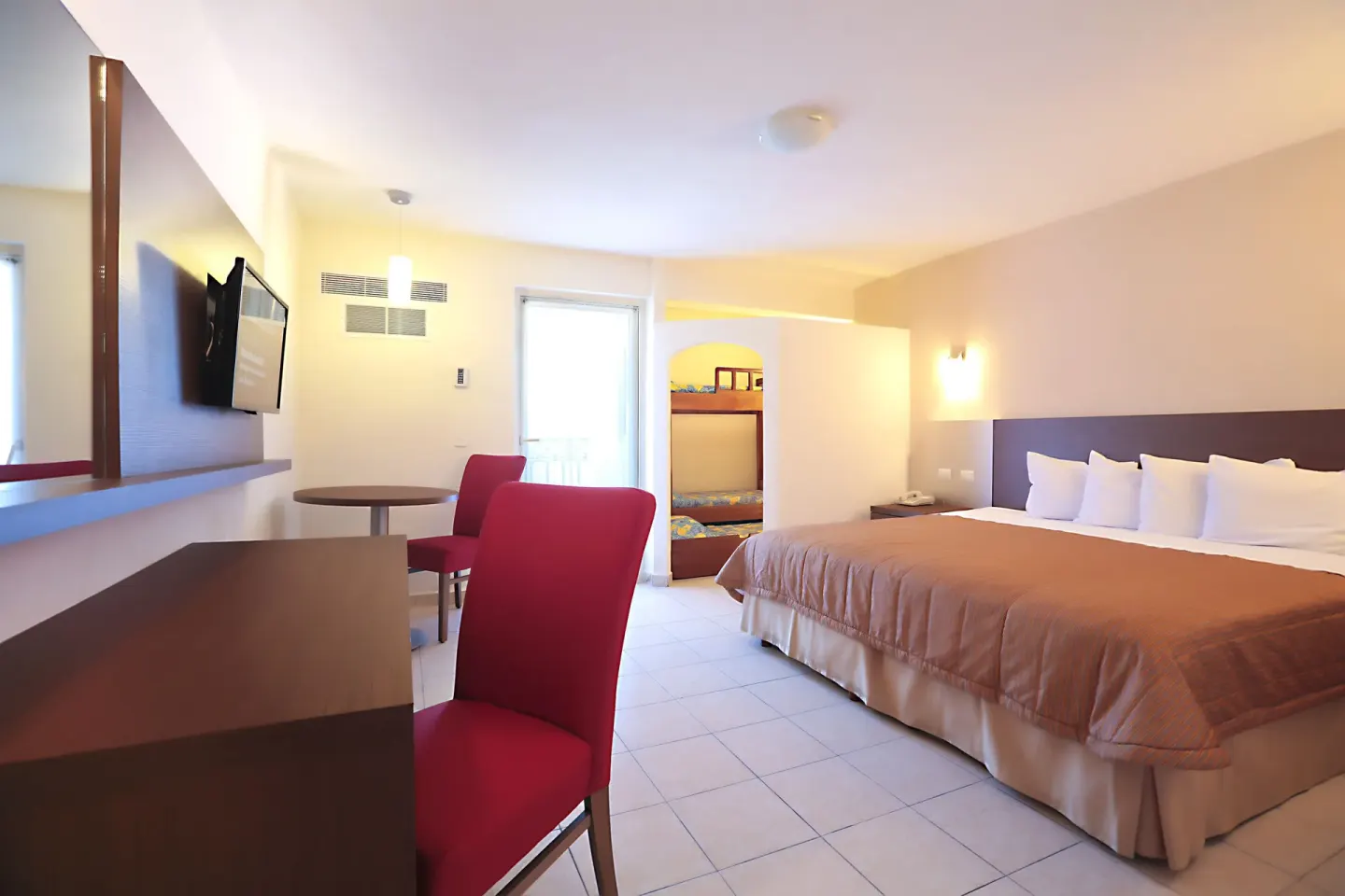 Family guest room with king bed, bunk beds, desk and dining table at Crown Paradise Club Puerto Vallarta.