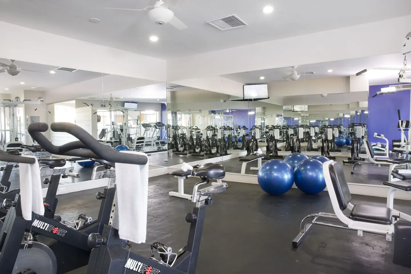 Fitness room with bikes, benches, mirrors, and exercise balls at Crown Paradise Club Puerto Vallarta.