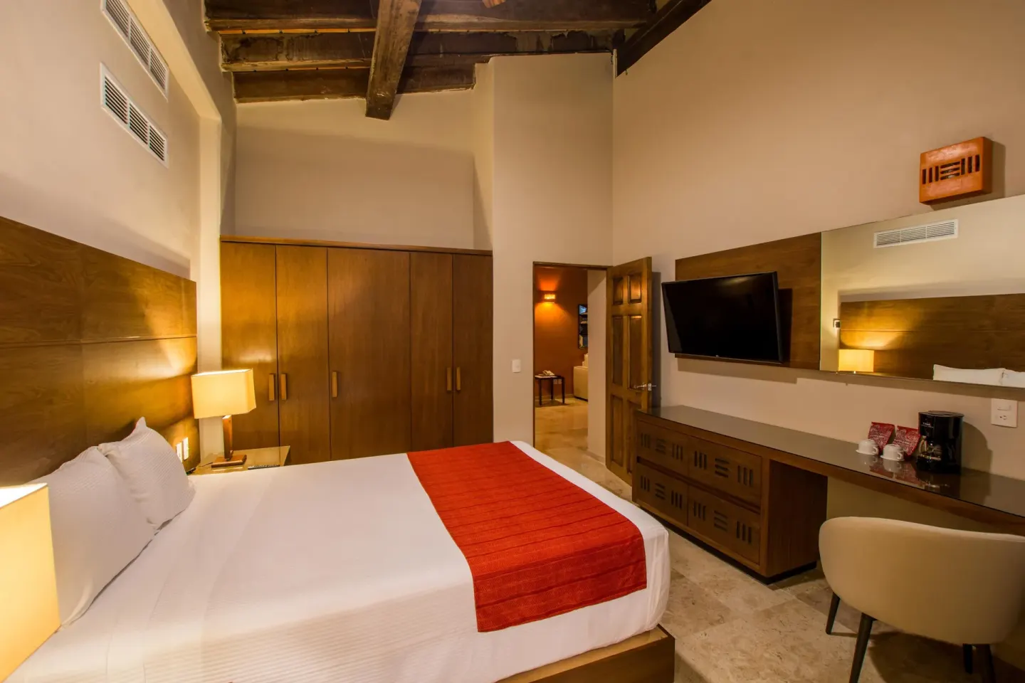 King bed guest room with wardrobe and desk at Crown Paradise Club Puerto Vallarta.