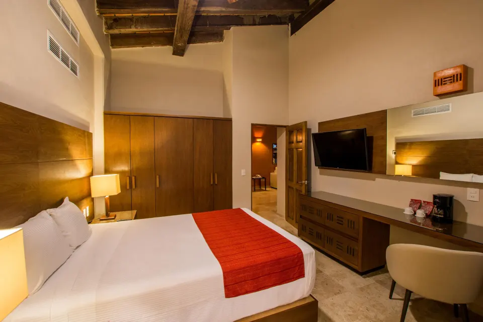 King bed guest room with wardrobe and desk at Crown Paradise Club Puerto Vallarta.