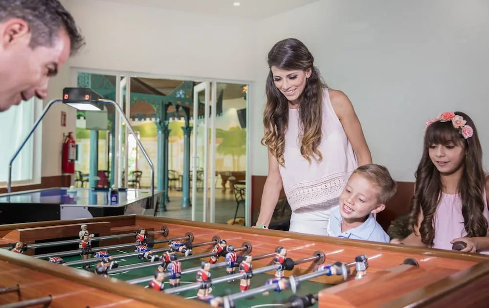 Family playing foosball in an indoor game area at Crown Paradise Club Puerto Vallarta.
