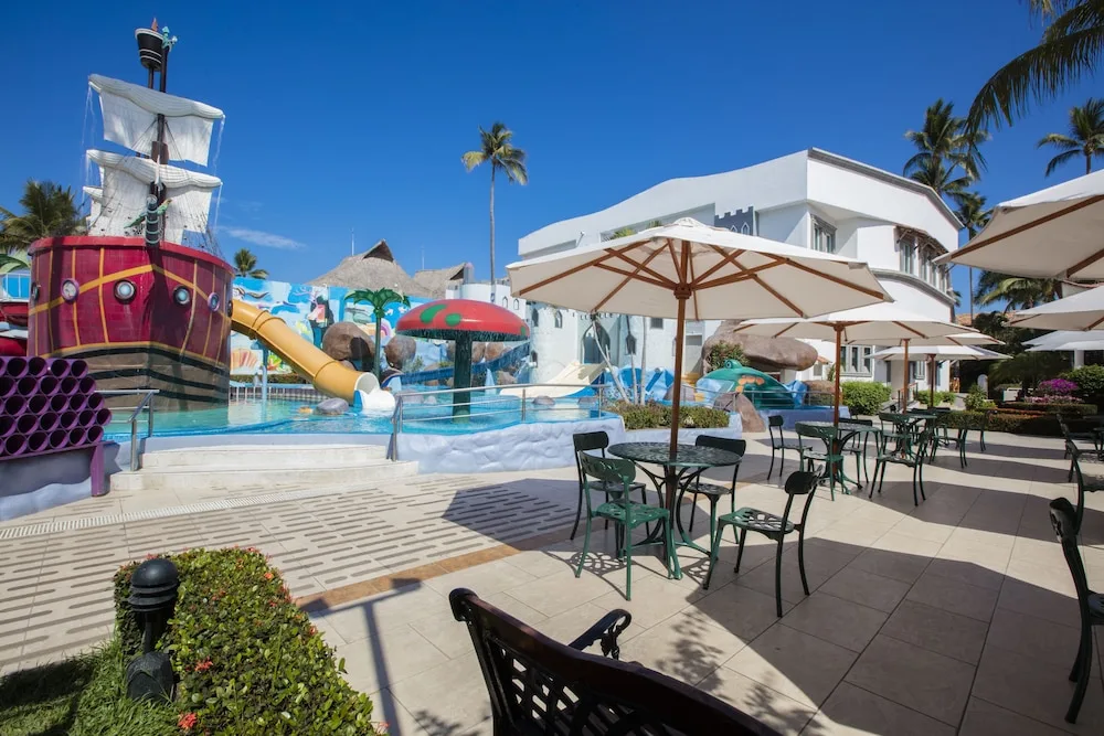 Pirate ship water play area beside patio tables at Crown Paradise Club Puerto Vallarta.