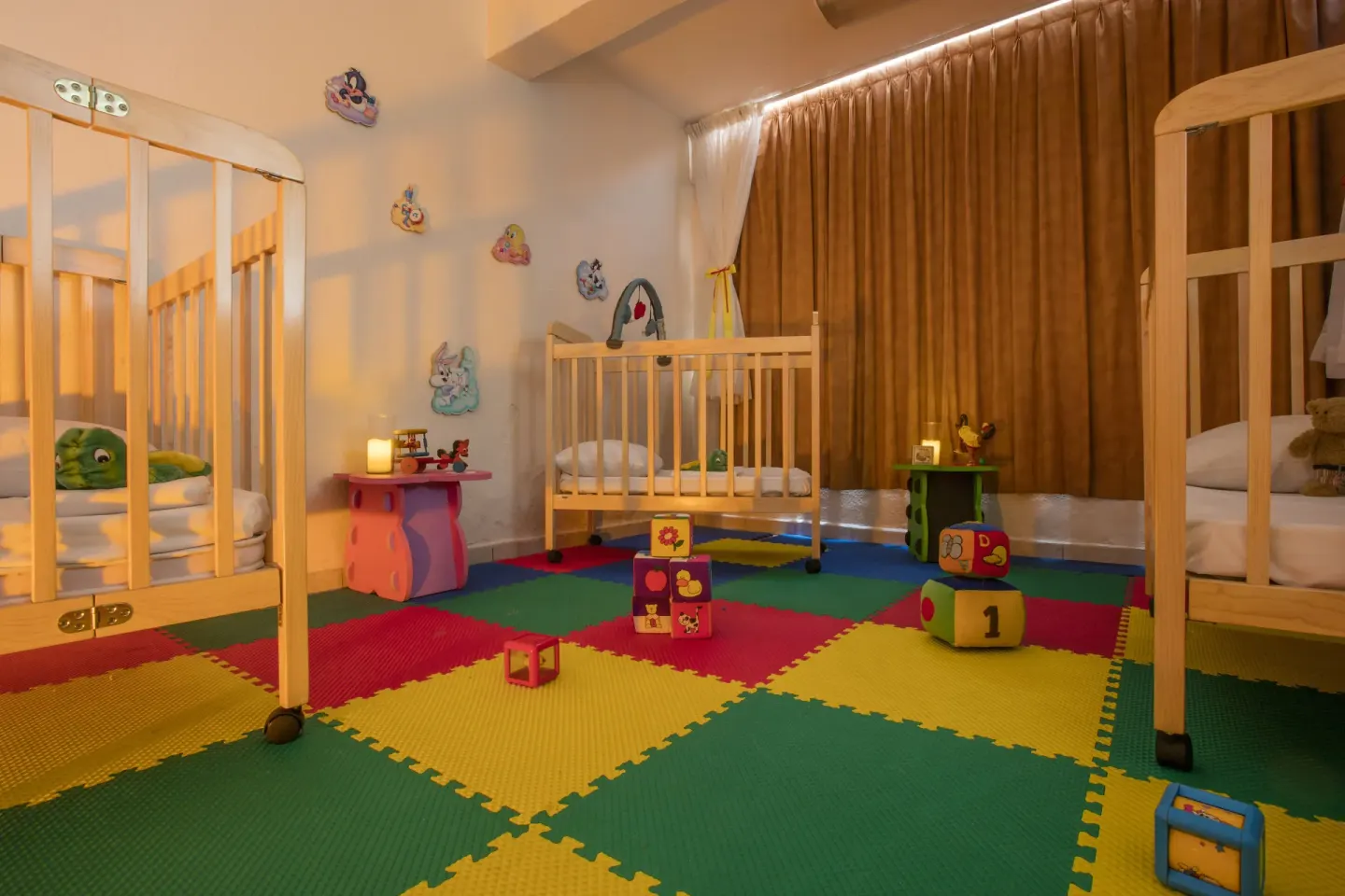 Nursery playroom with cribs and foam mats at Crown Paradise Club Puerto Vallarta.