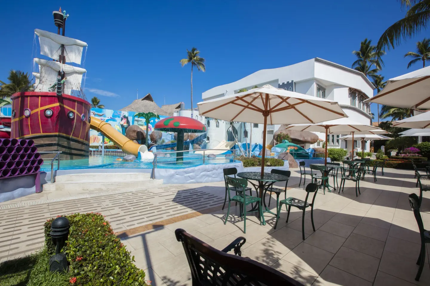 Pirate ship splash pool beside umbrella tables at Crown Paradise Club Puerto Vallarta.