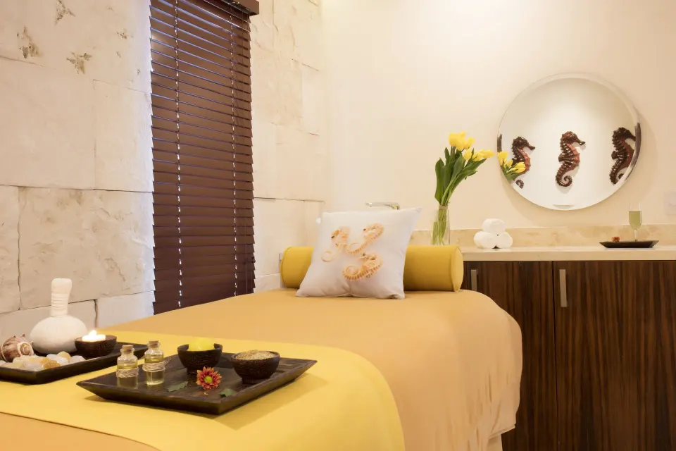 Spa treatment room with a yellow massage bed at Crown Paradise Club Puerto Vallarta.