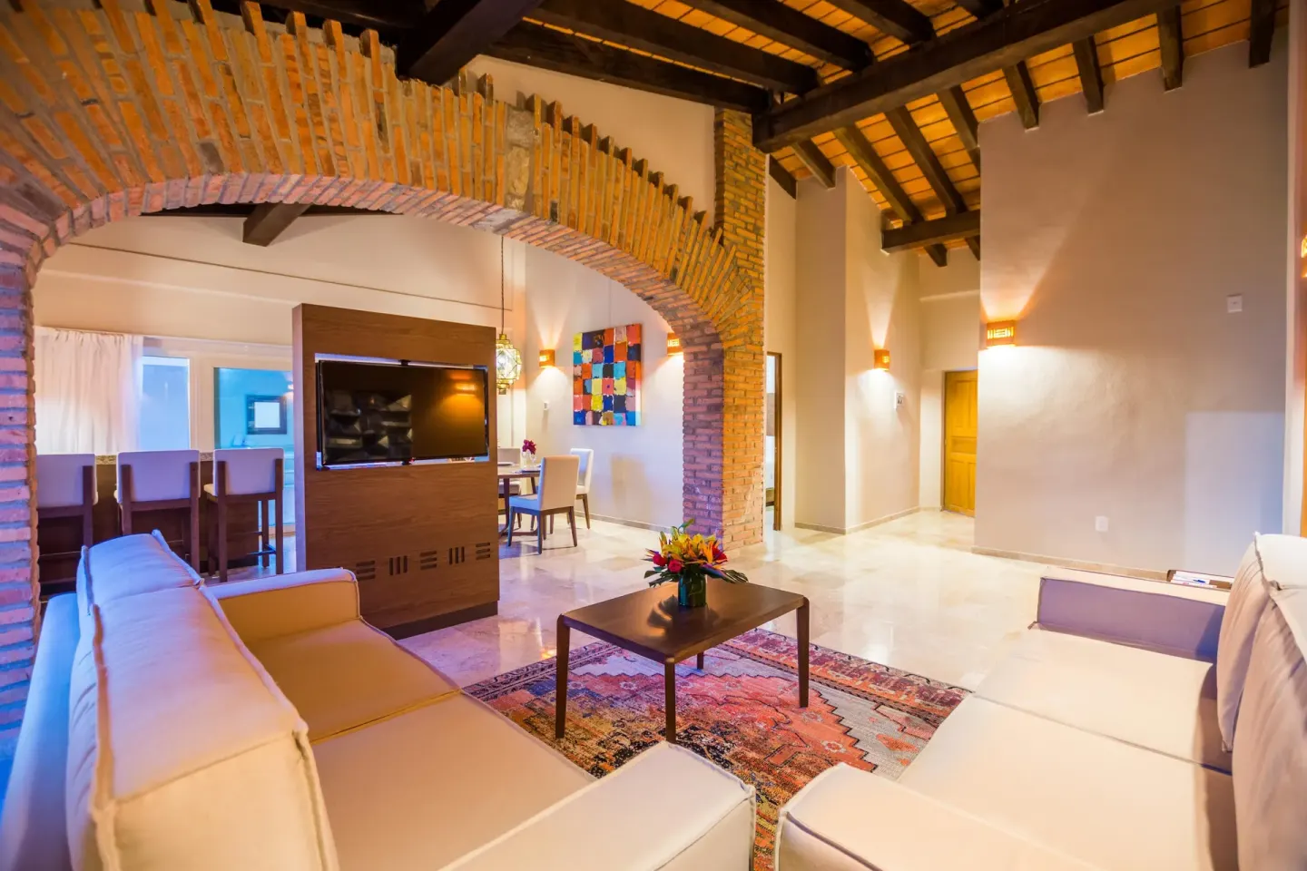 Spacious suite living area with brick arch, sofas and dining area at Crown Paradise Club Puerto Vallarta.
