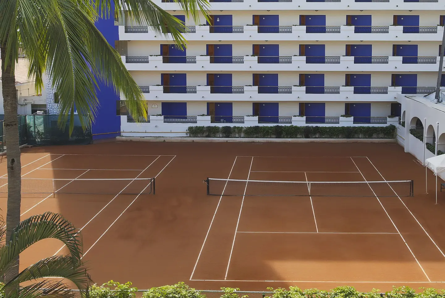 Tennis courts beside the guest-room building at Crown Paradise Club Puerto Vallarta.