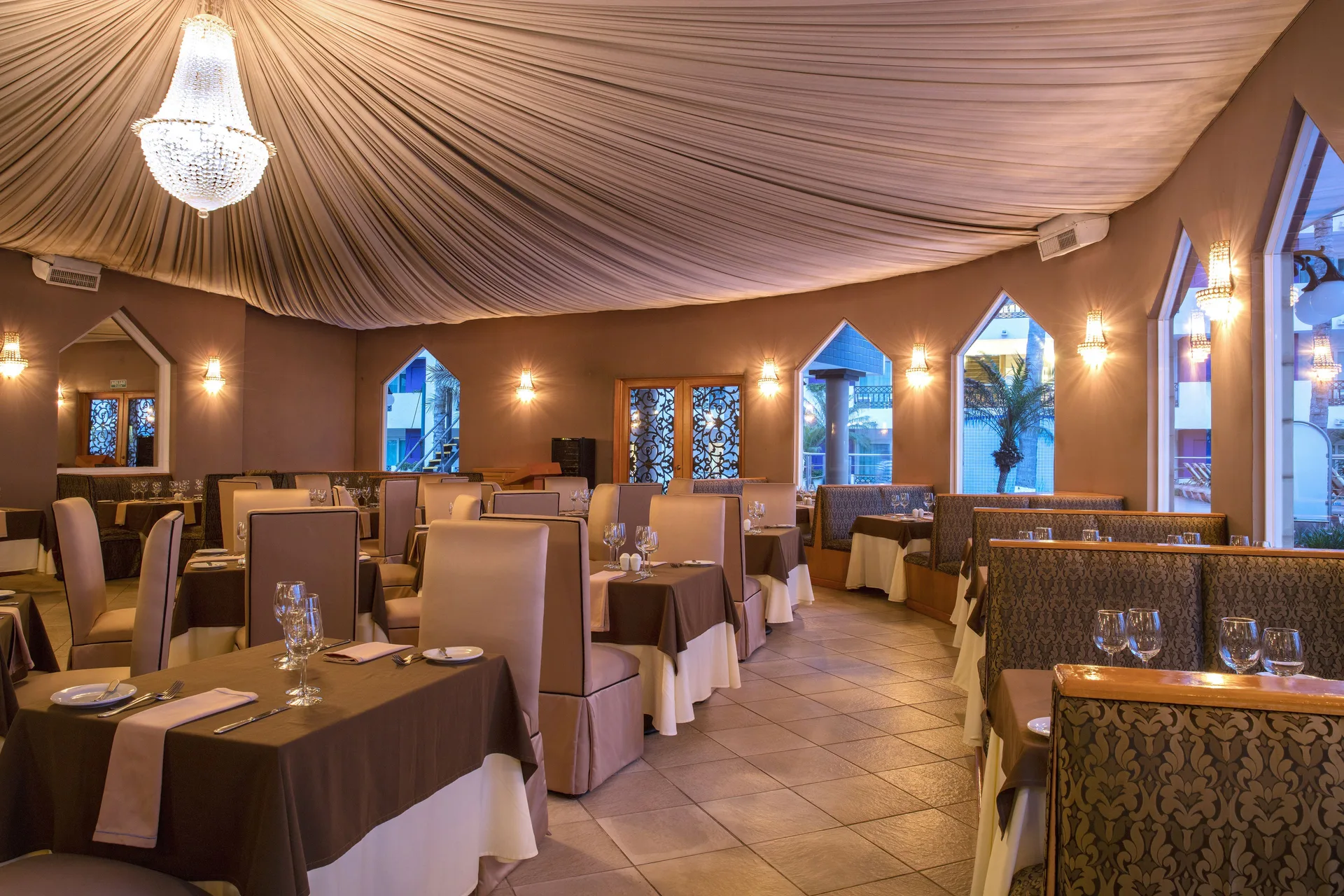 Elegant dining room with chandelier and draped ceiling at Crown Paradise Club Puerto Vallarta.