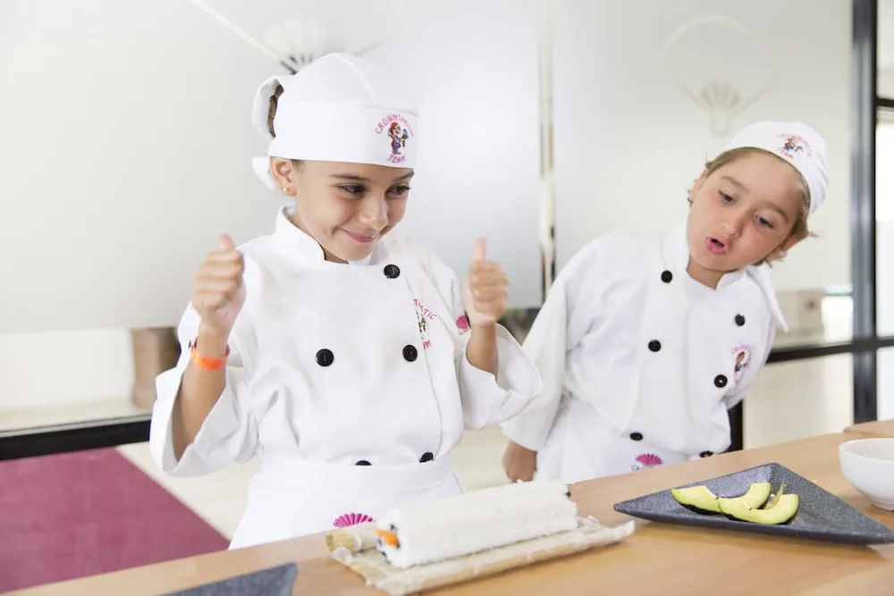Children in chef uniforms preparing sushi at Crown Paradise Club Puerto Vallarta.
