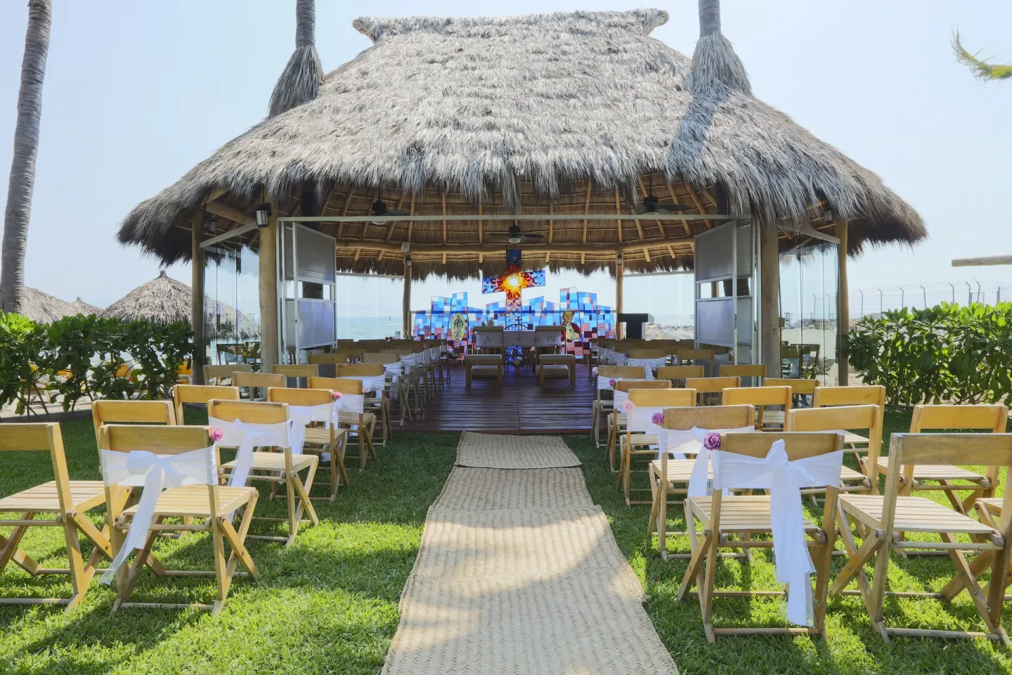 Beach wedding setup under a thatched palapa at Crown Paradise Club Puerto Vallarta.