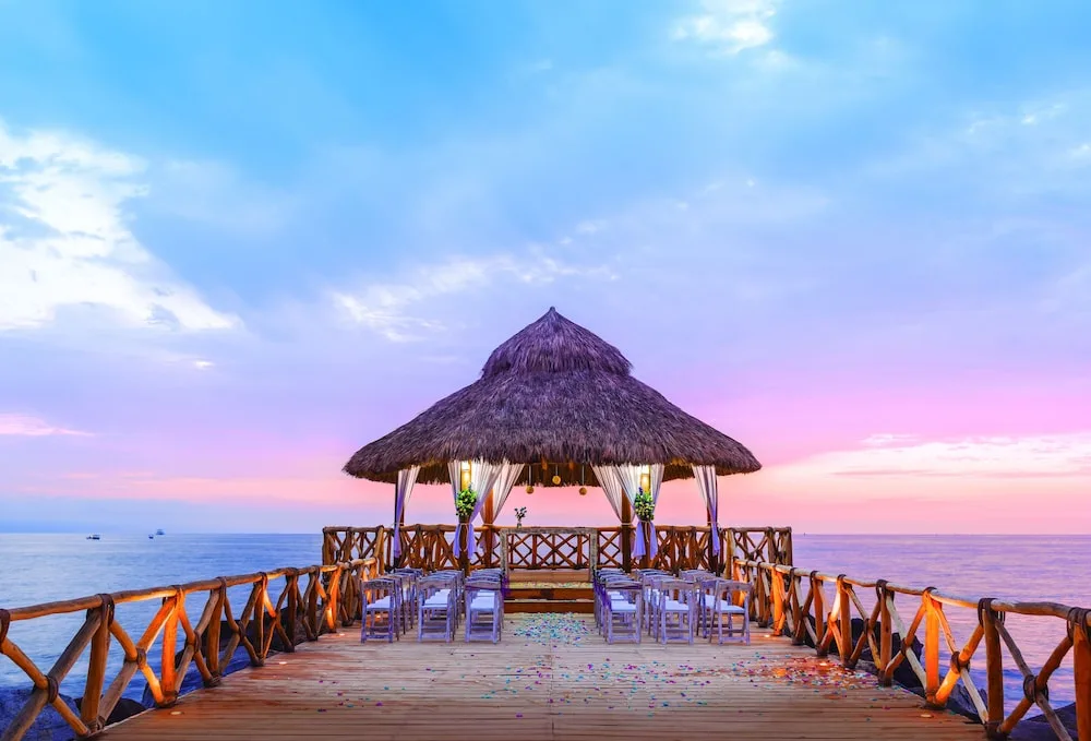 Oceanfront wedding pier with a thatched gazebo at Crown Paradise Club Puerto Vallarta.