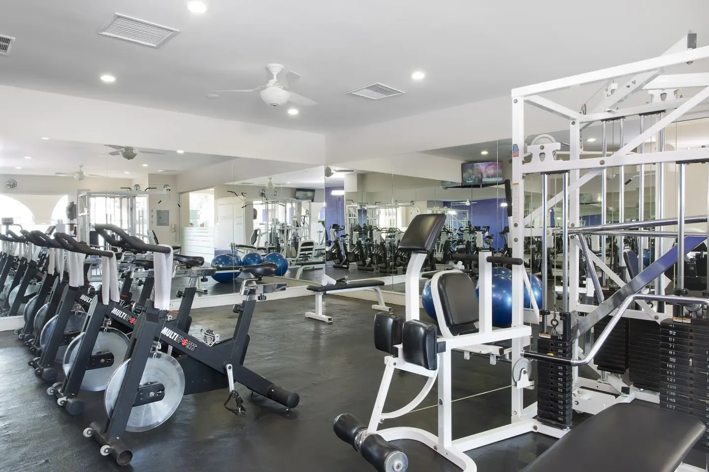 Fitness room with bikes, weight machine, mirrors, and exercise balls at Crown Paradise Golden Resort.