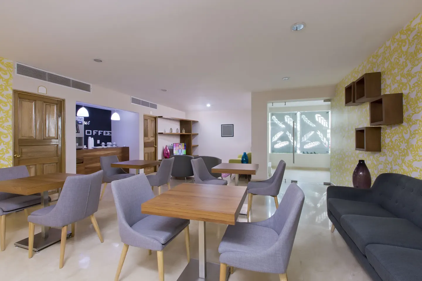 Indoor lounge with tables, chairs, sofas and a coffee counter at Crown Paradise Golden Resort.