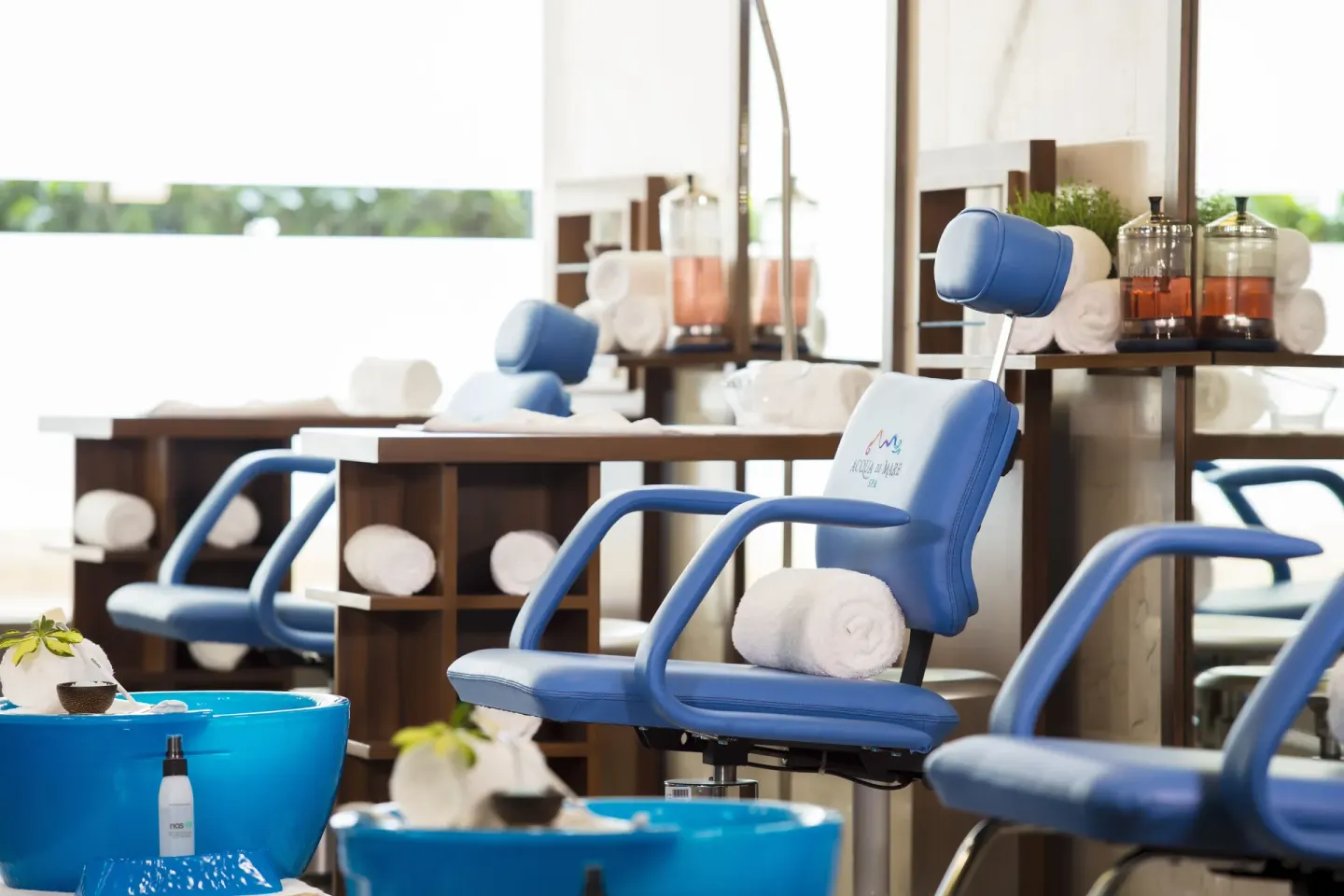 Spa pedicure chairs with blue basins and rolled towels at Crown Paradise Golden Resort.