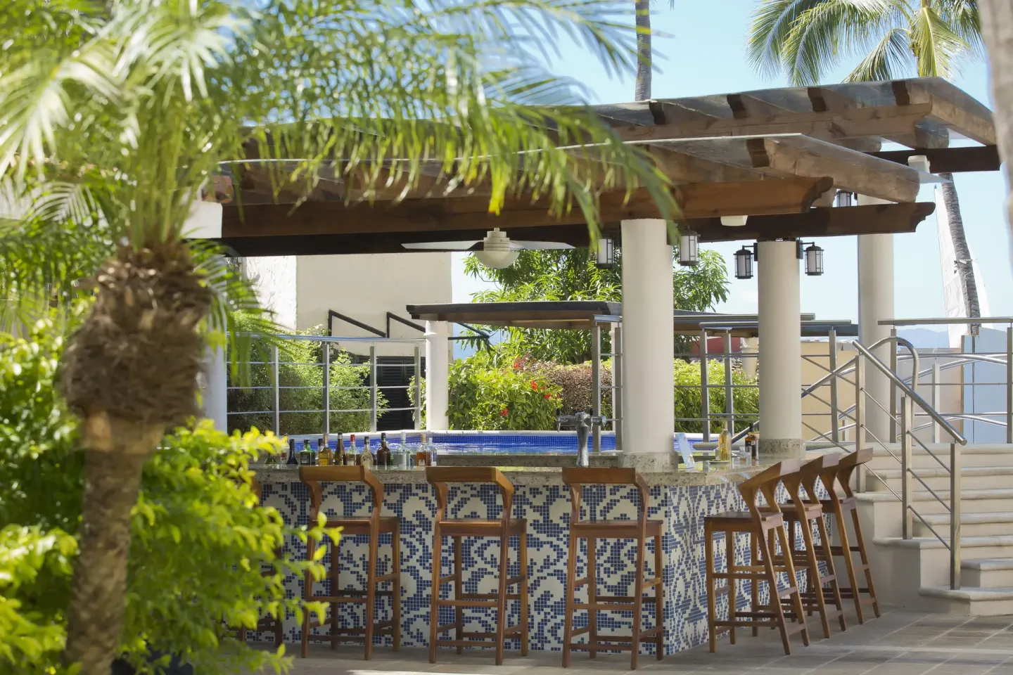 Poolside bar with mosaic tile counter and wood stools at Crown Paradise Golden Resort.