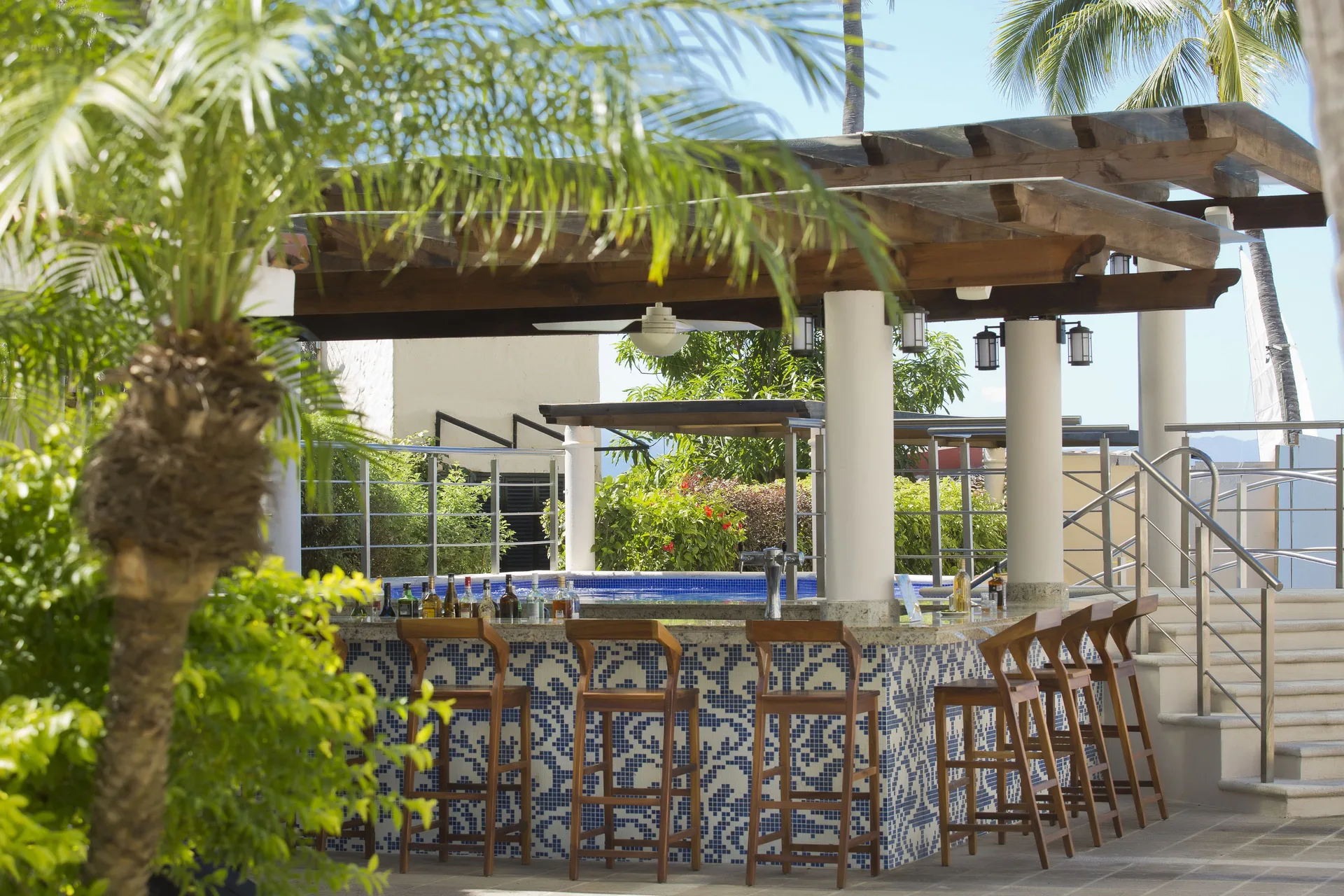 Poolside bar with mosaic tile counter and wood stools at Crown Paradise Golden Resort.