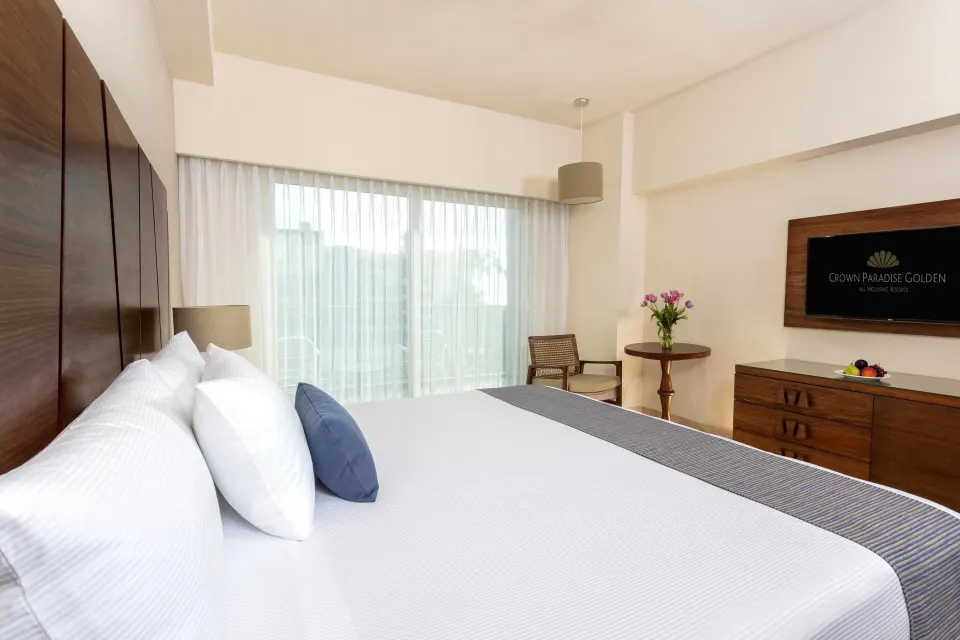 Deluxe Room king bed beside balcony curtains at Crown Paradise Golden Resort.