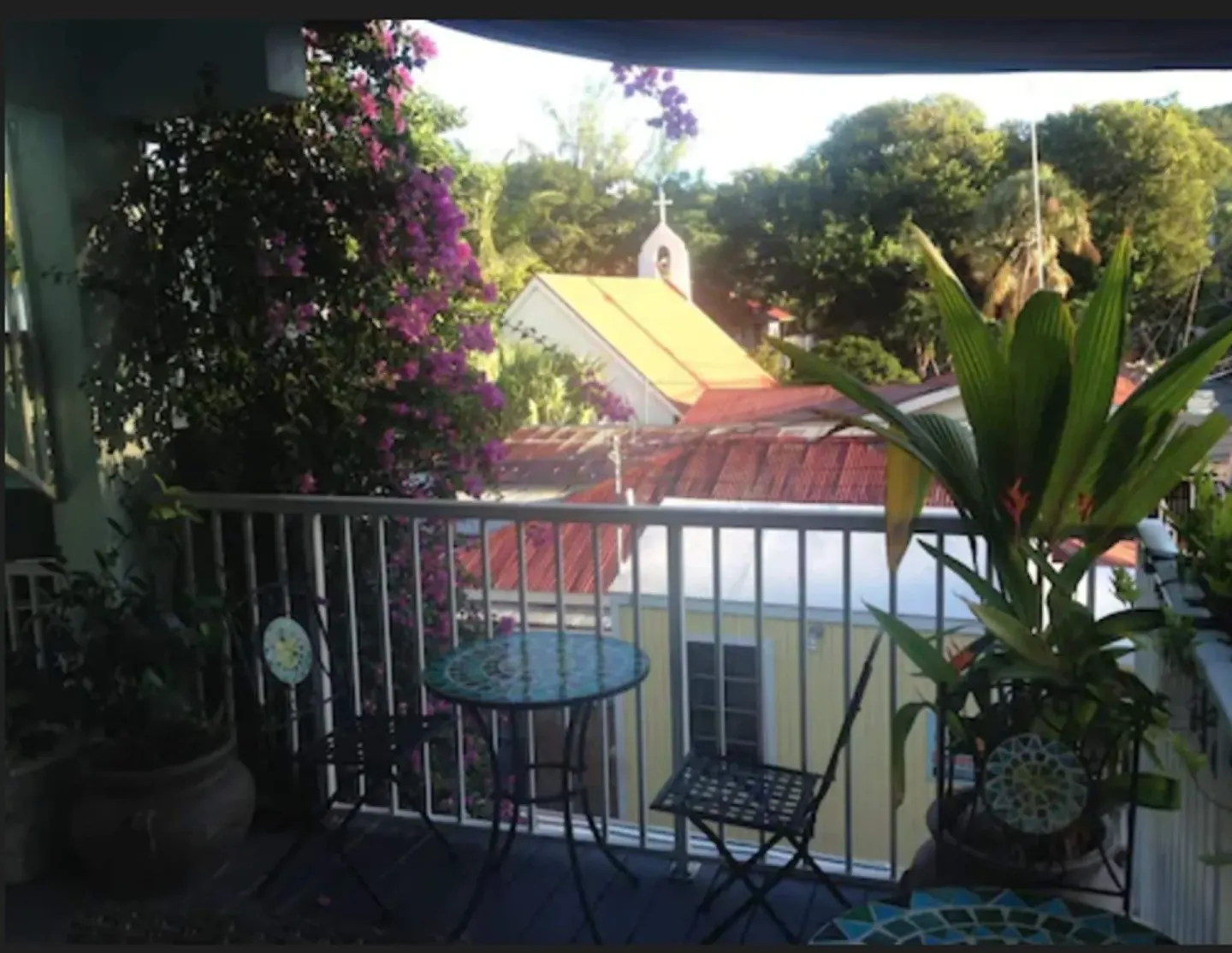 Balcony seating with potted tropical plants at Cruz Bay Boutique Hotel.