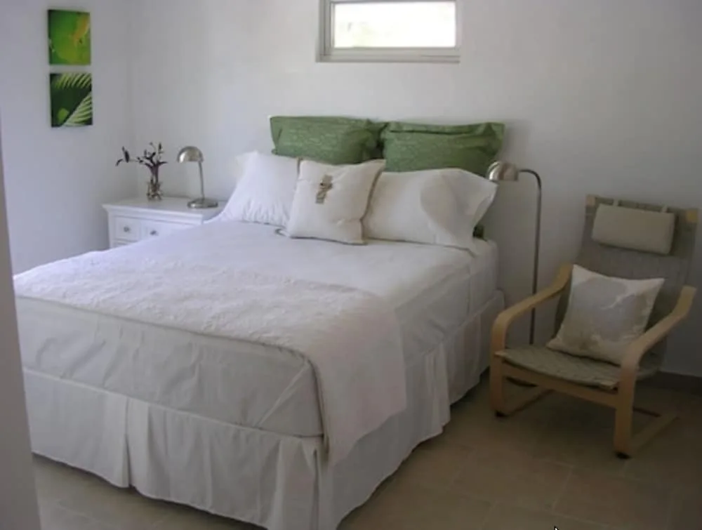 Guest room with a white bed, green pillows, chair, and wall art at Cruz Bay Boutique Hotel.