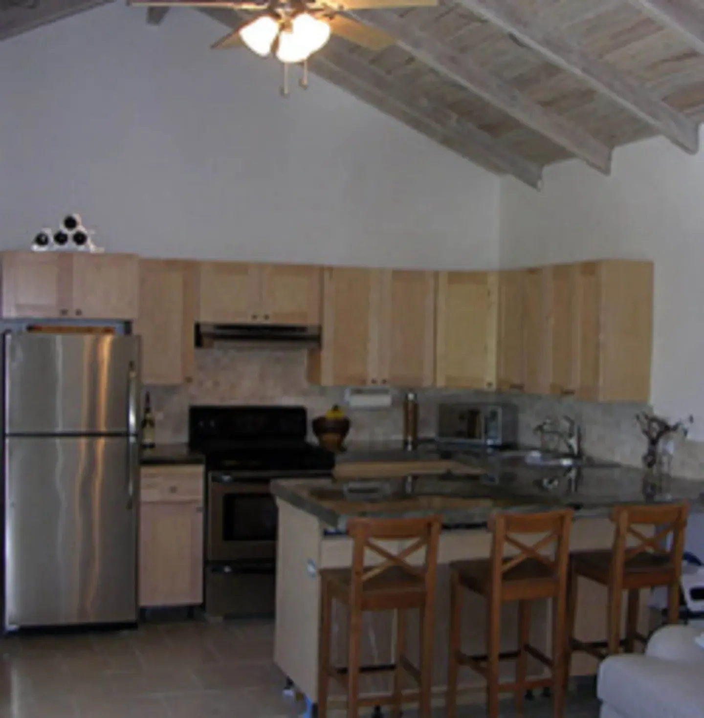 Kitchen with wood cabinets, island seating, and appliances at Cruz Bay Boutique Hotel.