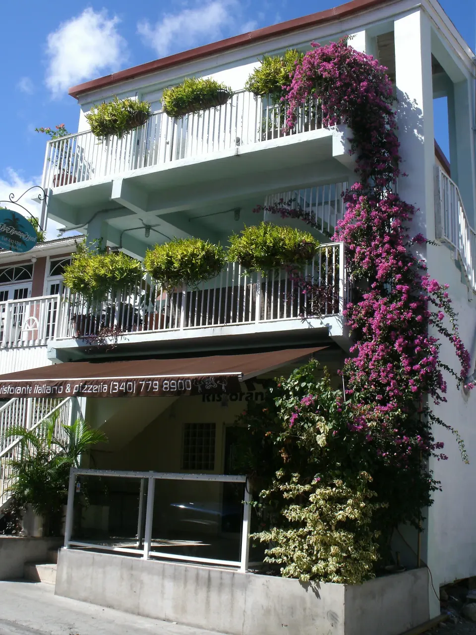 Street-facing hotel exterior with balconies and bougainvillea at Cruz Bay Boutique Hotel.