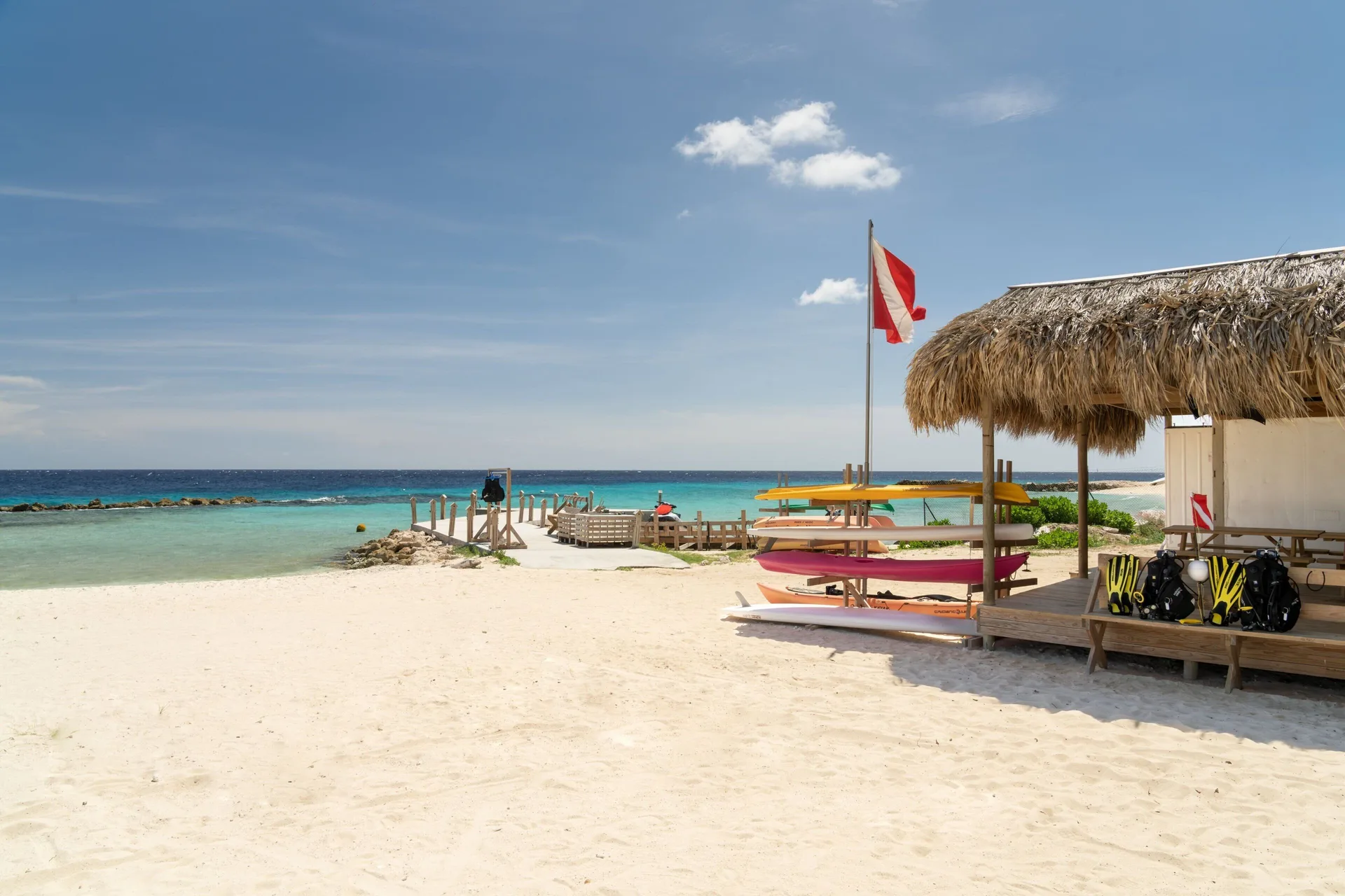 Sandy beach with thatched shade, kayaks, and turquoise water at Curacao Marriott Beach Resort.