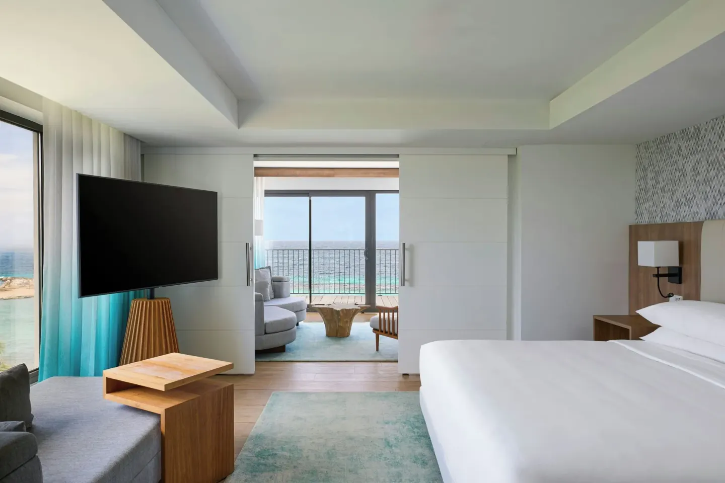 King bed and sitting area with ocean-facing balcony at Curacao Marriott Beach Resort.