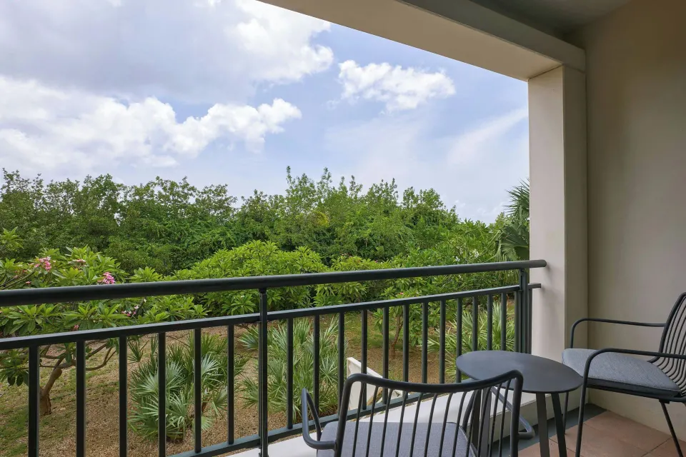 Covered room balcony with chairs and garden view at Curacao Marriott Beach Resort.