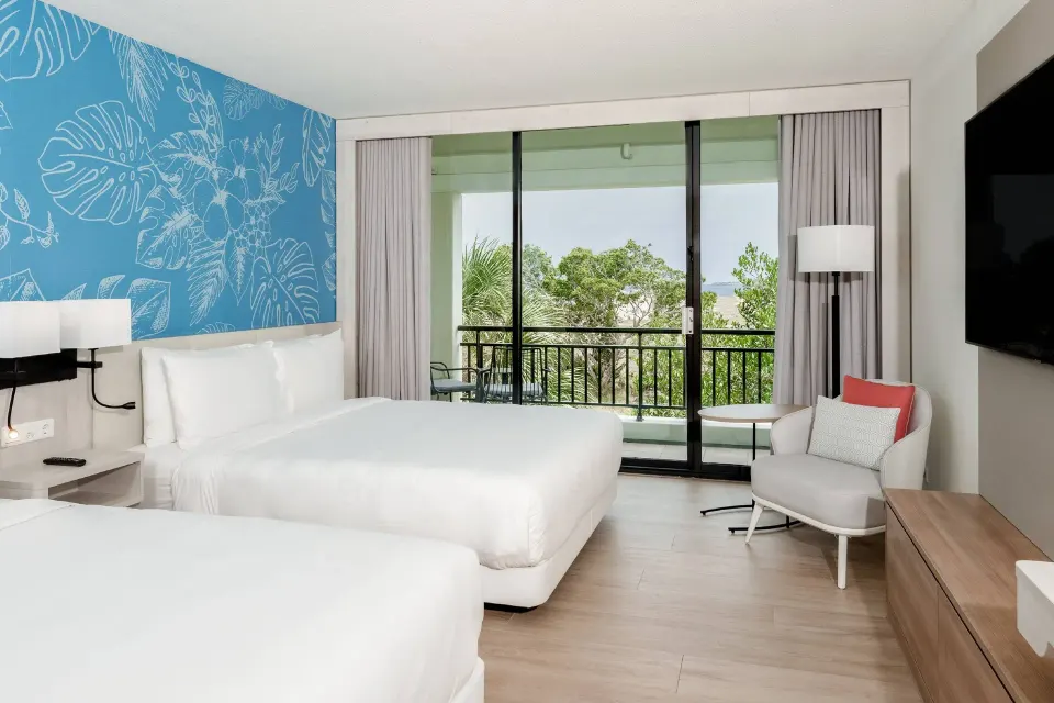 Two-bed guest room with balcony and limited greenery view at Curacao Marriott Beach Resort.