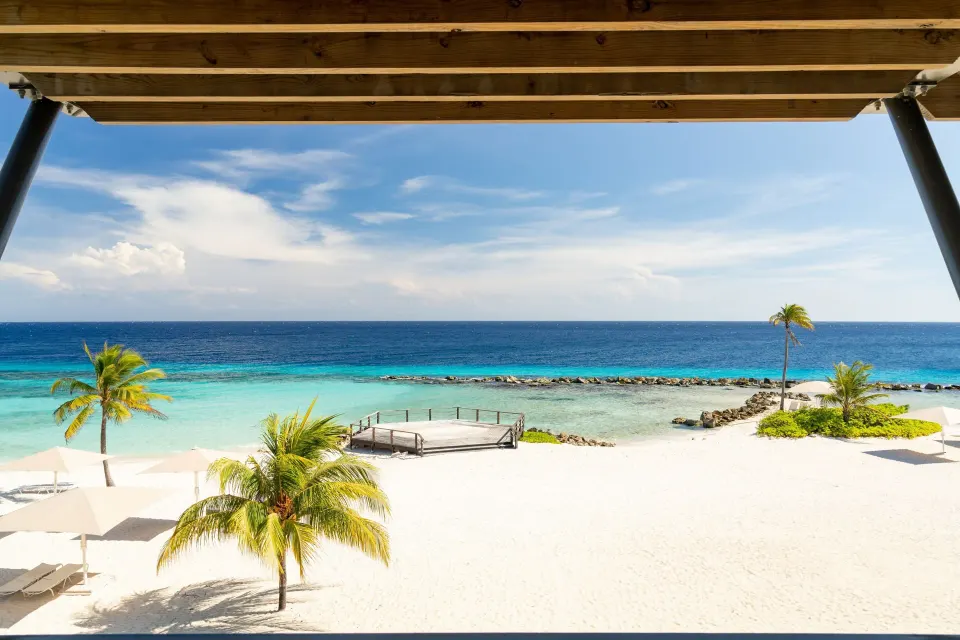 Oceanfront room balcony view at Curacao Marriott Beach Resort overlooking palms, beach, and sea.