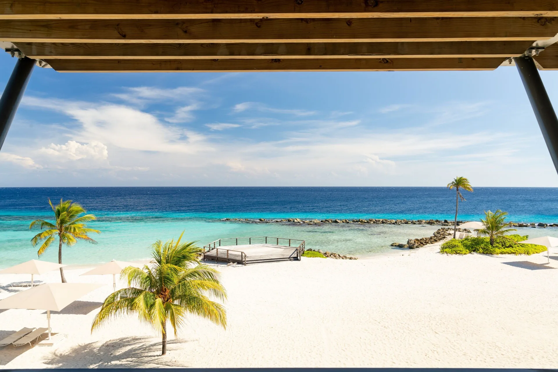 Oceanfront room balcony view at Curacao Marriott Beach Resort overlooking palms, beach, and sea.