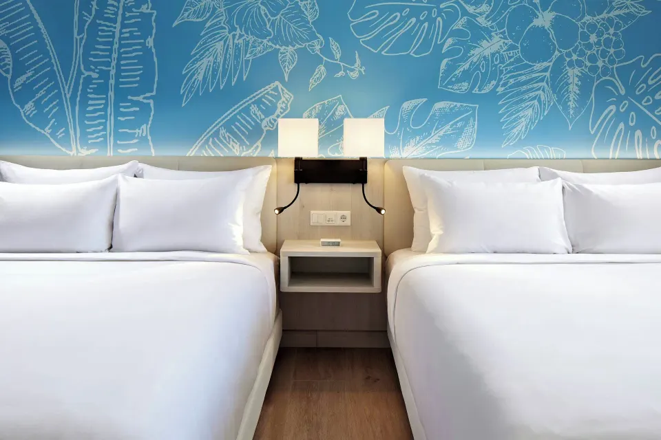 Two beds in an oceanfront room at Curacao Marriott Beach Resort with a blue tropical wall mural.