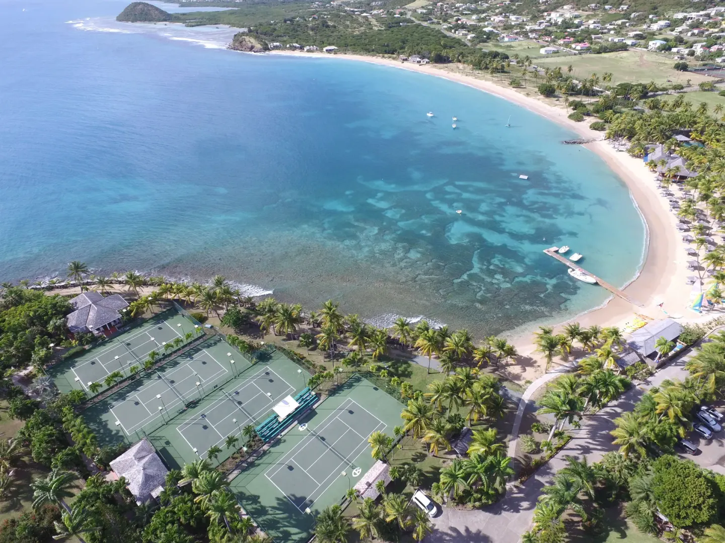An aerial view shows the bay, beach, and tennis courts at Curtain Bluff Resort.