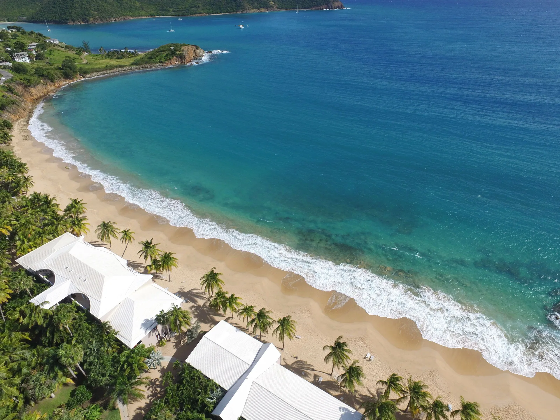 Aerial view of the beach, palms, and turquoise sea at Curtain Bluff Resort.