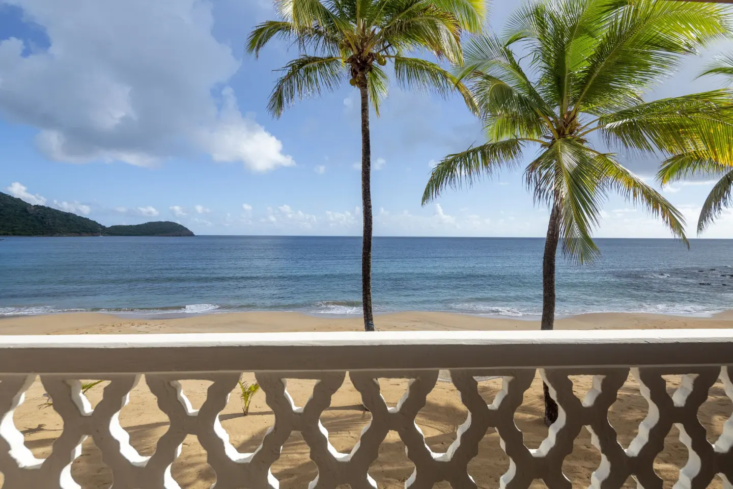 Balcony view of palm trees, beach, and ocean at Curtain Bluff Resort.