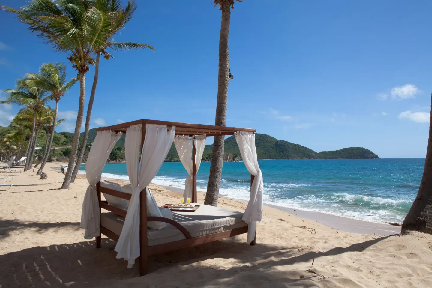 A curtained beach cabana faces the turquoise sea at Curtain Bluff Resort.